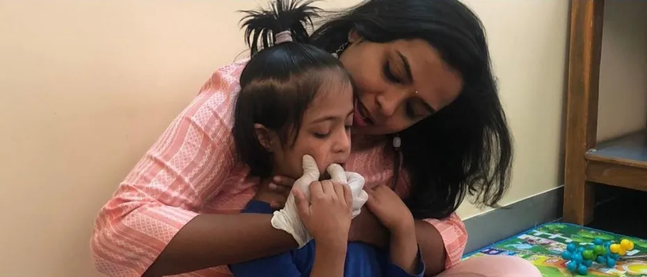A therapist gently supporting a young girl during feeding therapy