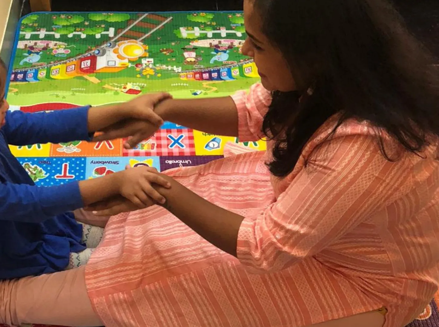 A therapist holding hands with a young girl during play